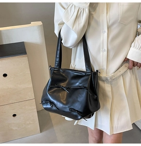 Detail of matte black PU leather tote bag with stylish decorative ribbon knots for women