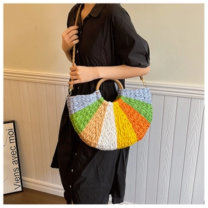 Detail of a rainbow color-blocked straw handbag with a round handle and strap