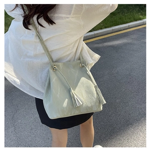 Détail d'un sac seau vert menthe avec texture marbrée et franges sur un modèle