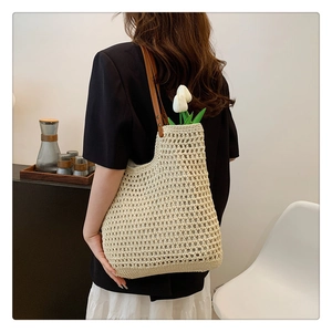 Detail of the woven texture and brown leather strap on a minimalist cream shoulder bag
