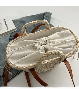 Detail of woven straw handbag featuring a drawstring lining and brown leather strap