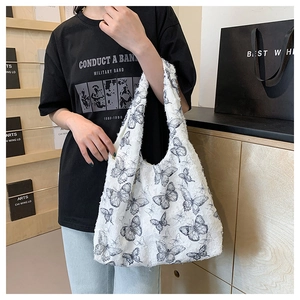 Detailed view of white fleece tote bag featuring black butterfly pattern worn by a model