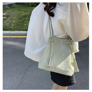 Vue détaillée d'un sac seau en cuir PU vert pâle avec des plis nuages et des glands