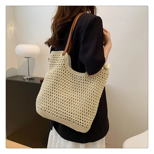 Detail of beige knit tote bag with mesh pattern and brown leather shoulder straps