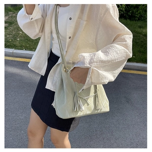 Détail d'un sac bandoulière en cuir PU vert clair brillant avec pendentif à franges