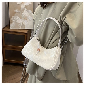 Detail of off-white hobo bag with floral patterns and pearl charm on a model