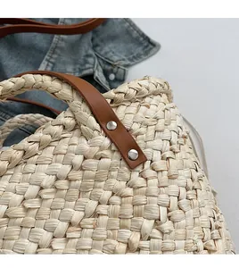Detailed close-up of straw woven texture with brown leather handle and silver rivets