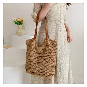 Detail of the hollow knit mesh texture and brown faux leather straps on a khaki tote bag