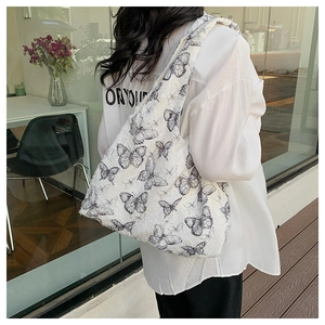 Lace style white shoulder bag featuring black butterfly patterns on a casual model outfit