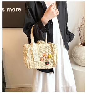 Détail de la texture en paille tressée avec appliques florales et ruban en dentelle du sac