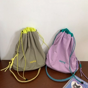 Sacs seaux minimalistes en nylon kaki et violet posés sur une surface en bois sombre