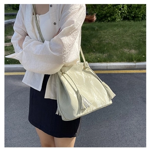 Détail du sac bandoulière en cuir PU vert clair avec glands latéraux et cordon de serrage
