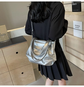 Close-up of a silver faux leather tote bag with bow details worn by a model