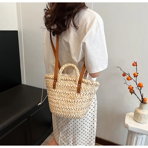 Detail of straw handbag featuring leather straps and white drawstring lining