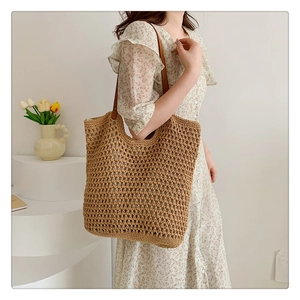 Detail of hollow out crochet tote bag featuring brown leather strap and rivet reinforcement