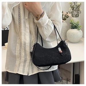 Close-up of black floral jacquard underarm bag with decorative beaded charms