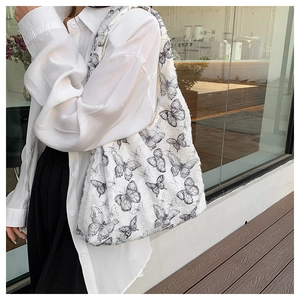 Detailed view of a white lace tote bag featuring elegant black butterfly print patterns