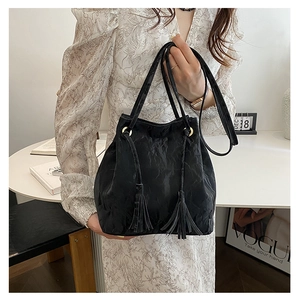 Détail du sac seau noir à cordon avec anneau doré et ornement de pompon à franges