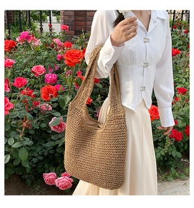 Vista dettagliata della grande borsa hobo in paglia intrecciata da donna in toni terra naturali