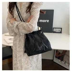Gros plan sur un sac bandoulière noir plissé en cuir PU avec détails de cordon à gland