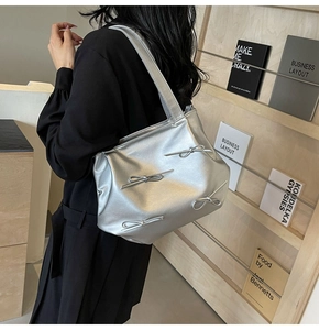 Detail of silver PU leather tote bag with 3D bows shown on a model's shoulder