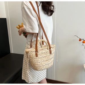 Detail of hand-woven straw tote with brown leather strap and drawstring lining