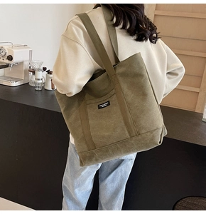 Olive green canvas tote bag with long shoulder strap shown in a cozy cafe setting