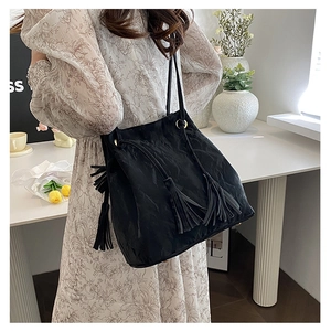 Détail du sac bandoulière noir en similicuir plissé avec pompons longs élégants