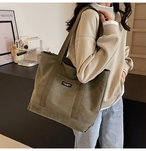 Close-up of army green canvas tote bag with brand patch and wide shoulder strap