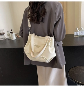 Detail of a creamy PU leather half-moon bucket bag with elegant ribbon bow decorations
