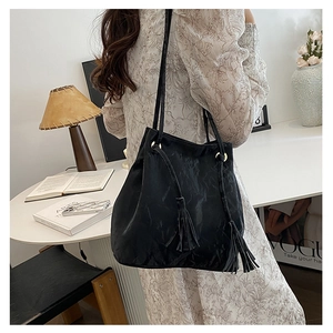 Vue détaillée du sac seau noir avec cordon à franges et détails métalliques dorés