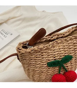 Close-up of straw bucket bag with knitted cherry decor and smooth metal zipper detail
