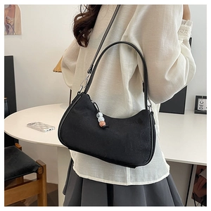 Detail of black canvas shoulder bag featuring creative bead charm and silver hardware