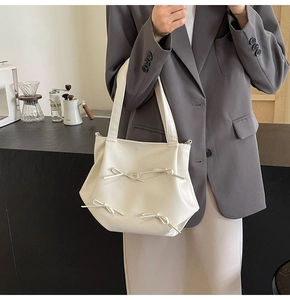 Detail of minimalist cream PU leather tote bag with elegant decorative bow accents