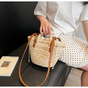 Detail of hand-woven straw bucket bag with brown leather straps and drawstring liner
