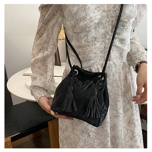 Détail du sac seau noir en similicuir plissé avec de longs glands et anneaux dorés
