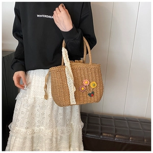 Gros plan d'un sac en paille tressée avec fleurs au crochet 3D et détail de foulard en dentelle