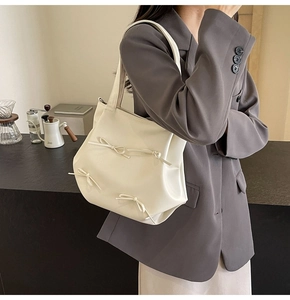 Detail view of cream PU leather tote bag with elegant bow accents and long shoulder strap