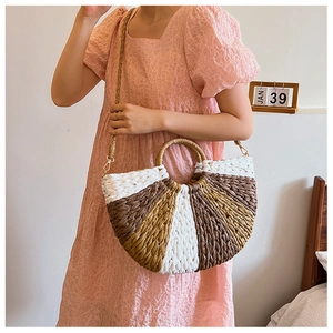 Detail shot of tricolor woven straw handbag with gold hardware on a lifestyle model
