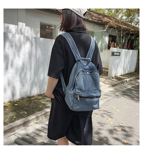 Outdoor shot of a vintage washed denim backpack with a large main pocket and wide straps