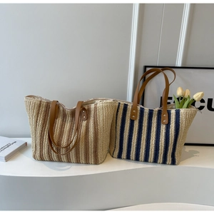 Detail of woven beach tote bags with leather handles and zip closure on a modern display