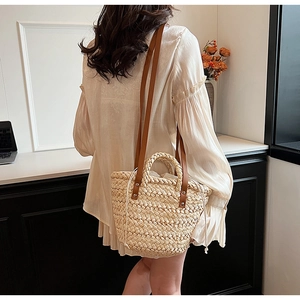Detail of straw woven tote bag with brown leather straps and drawstring closure