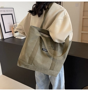 Model wearing a large army green canvas tote bag with adjustable shoulder strap detail