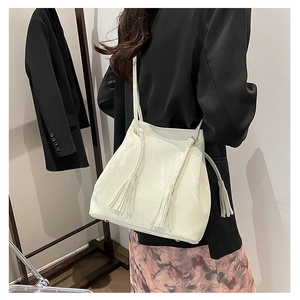 Détail d'un sac bandoulière blanc en cuir PU brillant avec cordon de serrage et pompons