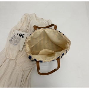 Flat lay showing interior lining with pocket and zipper of a striped straw tote bag