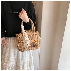 Détail du sac en paille tressée avec broderies florales faites main et ruban dentelle