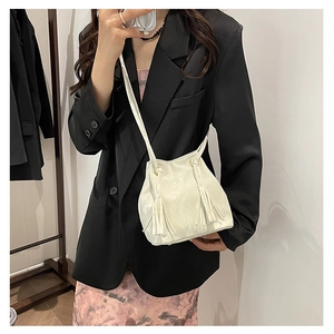 Sac seau blanc en similicuir avec franges porté par un mannequin pour l'effet de taille