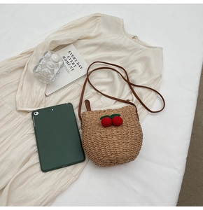 Detail of hand-woven bucket bag with crochet cherries and brown leather shoulder strap