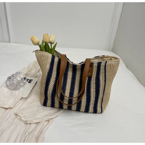 Detailed top view of striped straw tote bag with brown leather handles and zipper