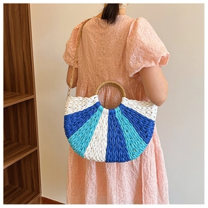 Detail showing handwoven striped straw handbag with round handle and adjustable shoulder strap